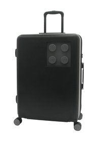 Svart hård resväska med fyra hjul, ett teleskophandtag och en frontpanel som har fyra texturerade, cirkulära LEGO-block.