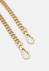 Due cinghie in tono oro con chiusure a molla su uno sfondo bianco, progettate per borse o accessori.