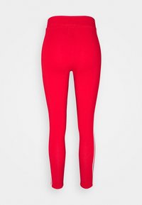 Červené sportovní legíny s vysokým pasem, vyrobené z pružného materiálu, se bílými bočními pruhy a přiléhavým střihem.