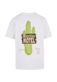 Bijela pamučna majica s grafikom zelenog kaktusa i smešnim tekstom "WESTERN MOTEL" te s dva izraza u žutoj boji, na jednostavnoj pozadini.