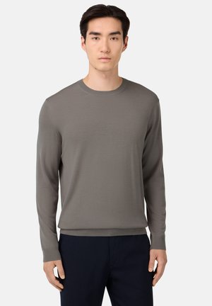 Maglione a maniche lunghe con scollo tondo in grigio tenue, caratterizzato da una texture liscia e polsini a coste, abbinato a pantaloni scuri.