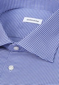 Chemise à motifs bleus et blancs avec col ouvert et boutons blancs, étiquetée "seidensticker" à l'intérieur du col.