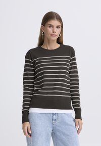 Temno sivi pleteni pulover z vodoravnimi belimi črtami, okrogel izrez, dolgi rokavi in rebrasti rob, nošen čez belo srajco.