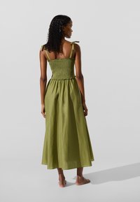 Roheline, keskmise pikkusega kleit, millel on korvitud ülaosa, õhukesed õlapaelad ja voolav seelik. Valmistatud kerge kangaga, mugava lõikega.