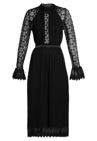 Robe en dentelle noire avec manches longues en dentelle à motifs, col montant et taille cintrée avec ceinture ruban. Jupe plissée texturée.