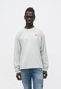 Hall hõlmikuga pikkade varrukatega särk, millel on punane "DIESEL" logo rinnal, kantud siniste teksadega; pehme tekstuur, lõõgastunud lõige ja juhuslik disain.