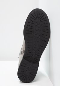 Scarpa in suede grigia con suola in gomma nera a contrasto caratterizzata da un motivo di presa testurizzato e chiusura con zip laterale.
