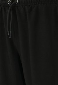 Svarta joggerbyxor med elastisk midja, justerbar dragsko och slät tygkvalitet. Har en enkel design utan utsmyckningar.