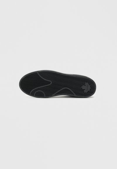 Talpă de sneaker neagră cu un model texturat în formă de pește. Prezintă o formă rotunjită și un material din cauciuc durabil. Detaliu de branding minimal.