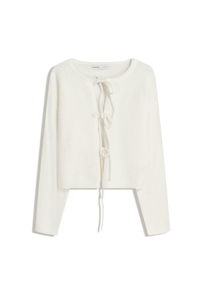 Gilet court à manches longues blanc avec col rond et trois fermetures à nouer à l'avant, en tissu tricoté doux.