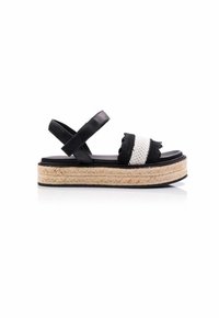 Sandalias de plataforma negras con plantilla de yute trenzado, que presentan una amplia correa tejida en blanco y negro y tiras cruzadas en el tobillo.