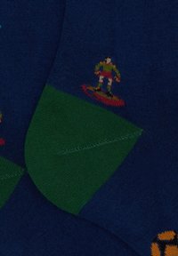 Calze blu marine con una sezione verde; presentano una grafica multicolore di un surfista e un logo circolare arancione su un lato. Texture liscia.