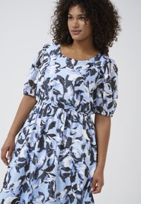 Light blue dress with a floral pattern in black and white, short puff sleeves, elastic waist, and flowing skirt. Smooth texture.