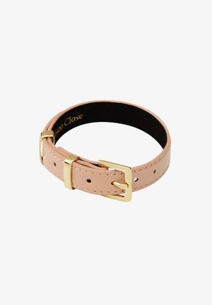 Collier pour animal en cuir rose clair avec boucle dorée et trous de réglage sur fond blanc.