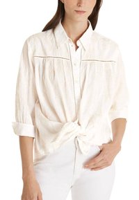 Weißes Hemd mit Knöpfen und strukturiertem Muster, mit gebundenem Vorderteil, hochgekrempelten Ärmeln und detaillierten Nähten entlang des Schulterbereichs.