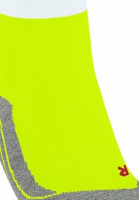 Helle gelbe Socke mit grauen Details, die Textur zeigt und ein kleines rotes Logo an der Seite hat, wodurch ihr Design und ihr sportlicher Zweck betont werden.