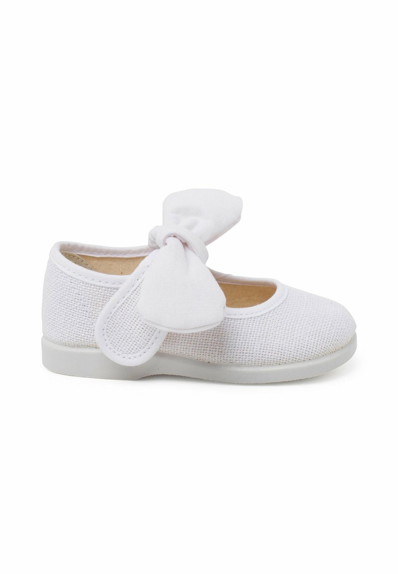 Zapato infantil blanco de malla con punta redondeada, suela de goma blanca y un lazo de tela a juego en el lateral.