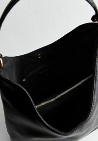 Bolso de mano de cuero negro con un bolsillo con cremallera dorada en el interior, textura suave, diseño espacioso y una sola correa para el hombro.