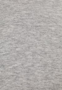 Jasnoszara dzianina z teksturowanym, lekko marmurkowym wzorem. Materiał wydaje się być miękki i elastyczny, odpowiedni do codziennej odzieży.