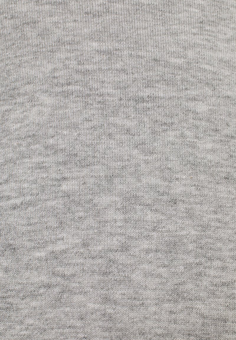 Tejido de punto gris claro con un patrón texturizado y ligeramente moteado. El material parece suave y elástico, adecuado para ropa casual.