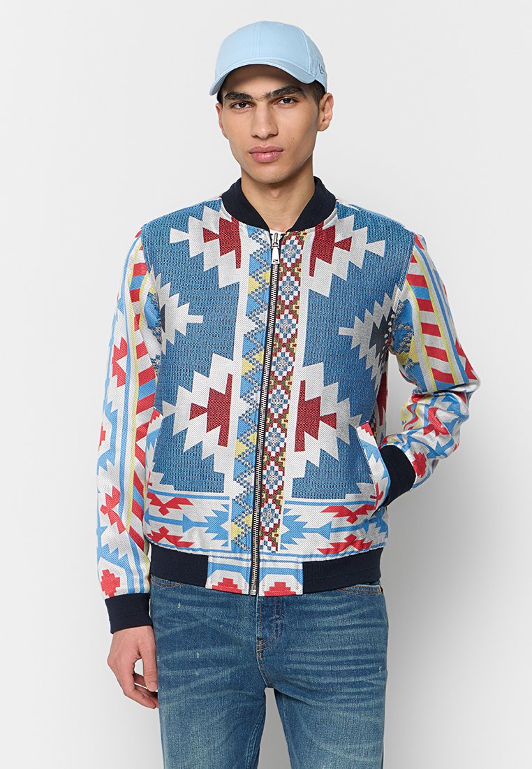 Bomberjack weet met een kleurrijk geometrisch patroon in blauw, rood en geel, met een rits aan de voorkant, geribde manchetten en zijzakken.