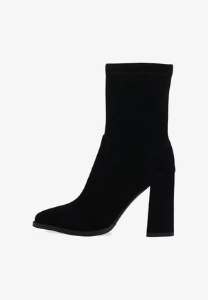Czarne zamszowe botki za kostkę z zwężającym się, stożkowatym czubkiem, wysokim słupkiem i dopasowaną cholewką. Posiadają przeszycie na mankiecie.