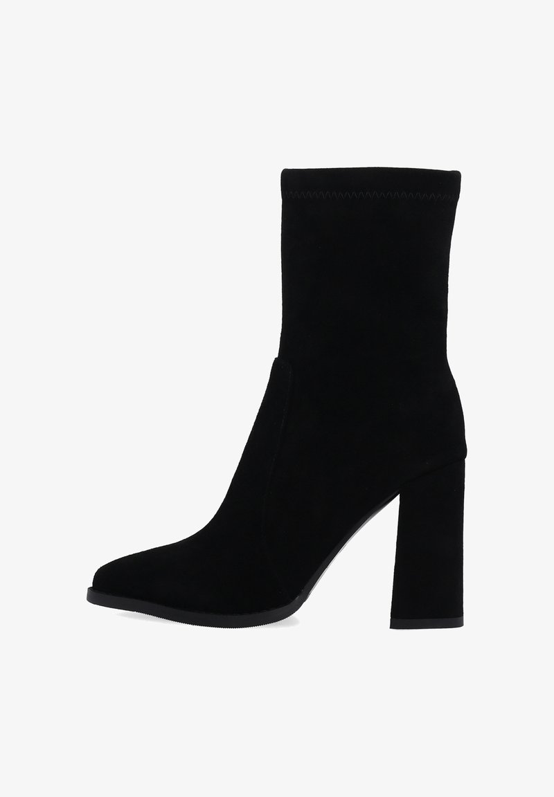 Černé semišové kotníkové boty s zužujícím se špičatým tvarem, vysokým blokovým podpatkem a upnutým svrškem. Obsahuje prošívání na manžetě.