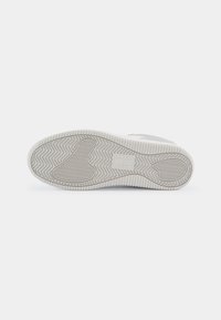 Suola di sneaker bianca con un motivo alla spina di pesce testurizzato. Presenta una punta rinforzata e bordi piatti, con un marchio sul sottopiede.
