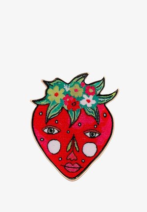 Spilla a forma di fragola con uno sfondo rosso che presenta un volto, foglie verdi sopra e decorazioni floreali colorate. Finitura lucida e con texture.