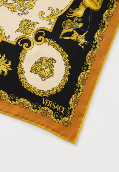 Γωνία μεταξωτού φουλαριού με χρυσά και μαύρα μπαρόκ σχέδια, έμβλημα κεφαλής Μέδουσας, μοτίβο άρματος τρένου, και λογότυπο Versace σε πορτοκαλί περίγραμμα.