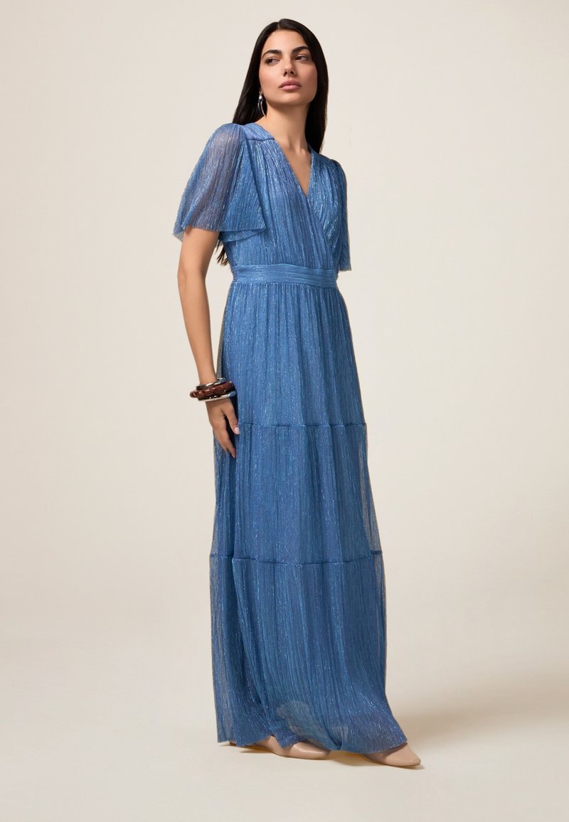 Rochie maxi albastră cu design stratificat și pliat, mâneci scurte și decolteu în formă de V. Realizată dintr-un material strălucitor și texturat. Detaliu neted la talie.