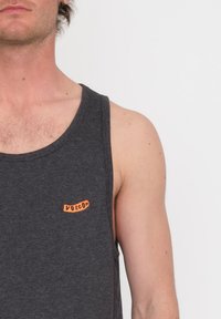Kulgrå tanktop med rund hals, der har et orange logo-patch med teksten "VOLCOM" på venstre brystområde. Blødt, letvægtsstof.