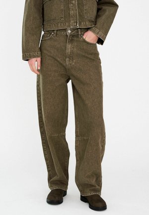 Olíva zöld farmerdzseki és hozzáillő, széles szárú nadrág, texturált felülettel, elülső zsebekkel és finom varrási részletekkel.