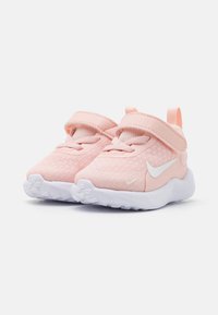 Baskets en mesh rose avec accents blancs, sangle ajustable et semelle blanche texturée. Bout arrondi et col rembourré pour le confort.