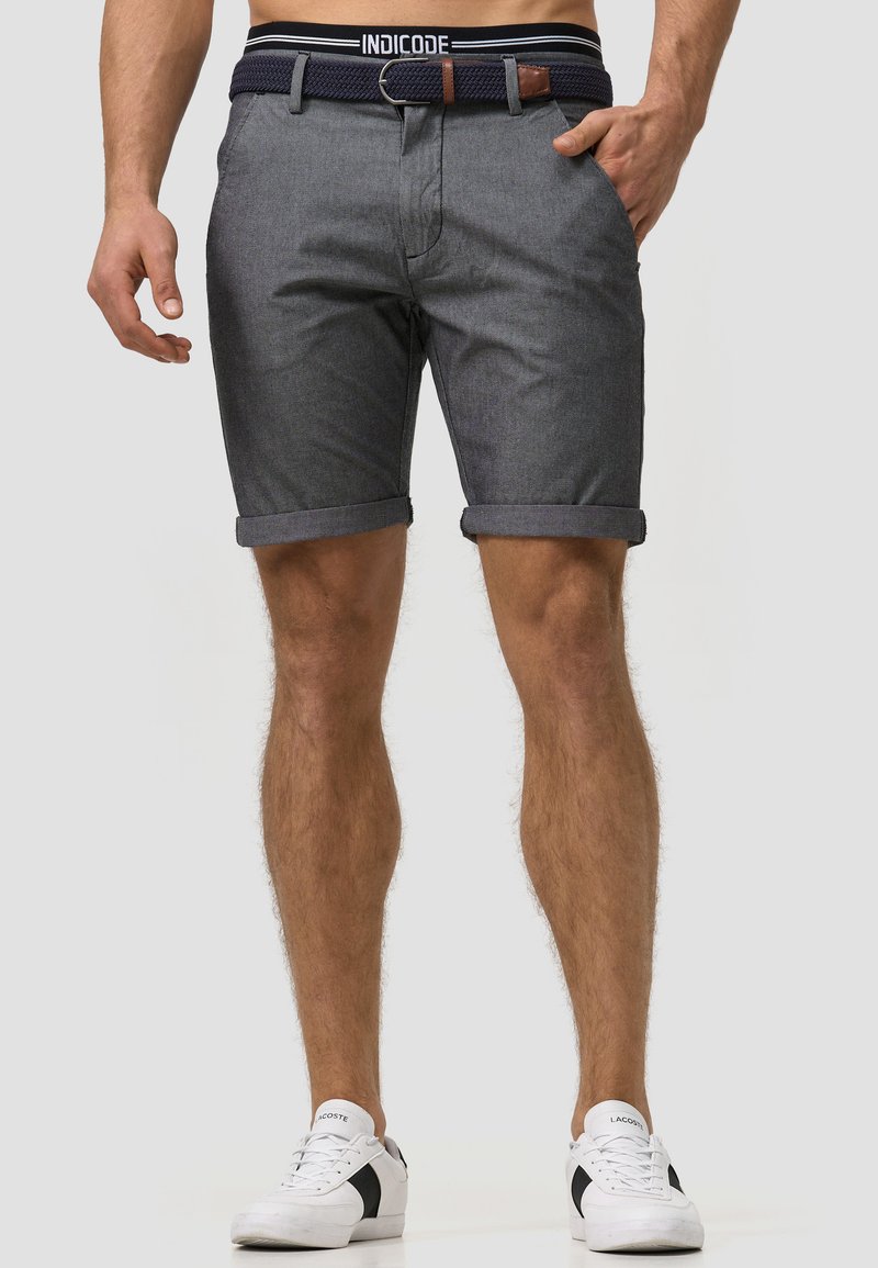 Shorts pour homme gris foncé avec revers, en tissu texturé. Dotés d'une ceinture tissée bleu marine avec un accent en cuir marron et une boucle en métal.