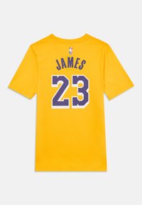 Geltonas medvilninis marškinėliai su užrašu "JAMES" purpurine spalva ir dideliais purpuriniais kontūriniais skaičiais "23" ant nugaros. NBA logotipas prie kaklo.