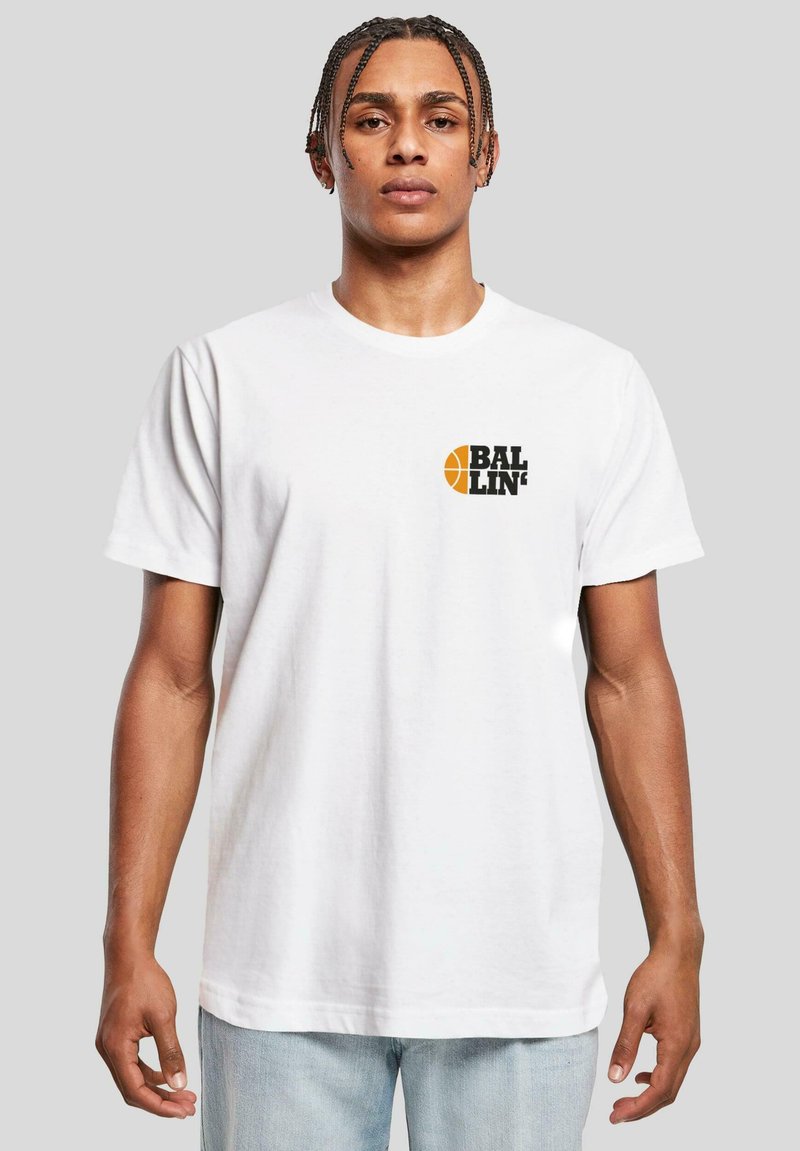 T-shirt en coton blanc avec un logo noir "BAL" et un graphique de basket-ball jaune sur la poitrine gauche. Manches courtes et coupe décontractée.