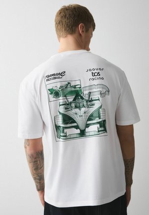 Mann trägt weißes T-Shirt mit grünen Drahtgitterzeichnungen eines Formel-E-Rennwagens und zugehörigen Logos auf dem Rücken.