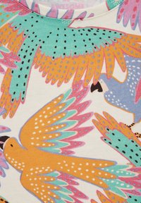 Top de tela de manga corta con un patrón de pájaros multicolores que incluye elementos en turquesa, naranja, rosa y gris sobre un fondo claro.