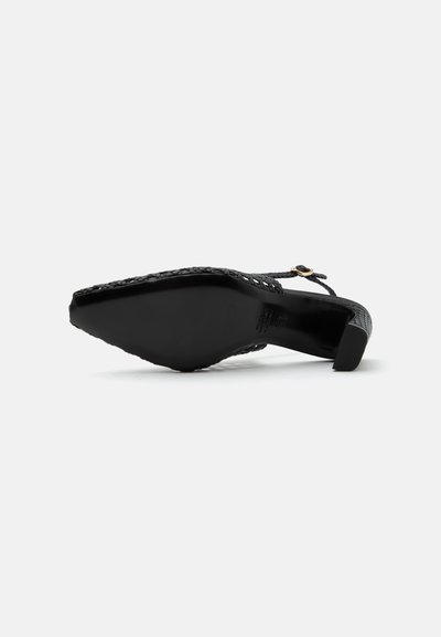 Escarpin slingback noir à bout pointu avec texture tissée et petite bride à boucle, vu du côté de la semelle sur fond blanc.