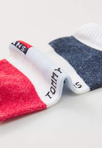 Colorful socks featuring red, white, and navy blue sections with a logo. Soft fabric with a ribbed ankle cuff for comfort.