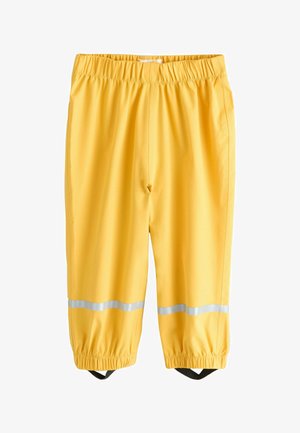 Żółte wodoodporne spodnie z elastycznym pasem i mankietami, z odblaskowymi paskami powyżej kostek oraz czarnymi paskami na stopy.