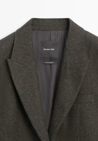 Czarna szara wełniana marynarka z wyłogami, widoczną podszewką oraz metkami z napisem "Massimo Dutti" i "Wyprodukowano w Portugalii."