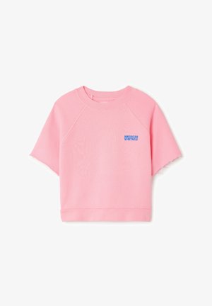 Różowa krótka bluza z okrągłym dekoltem, krótkimi raglanowymi rękawami i surowym wykończeniem dołu. Na przodzie znajduje się niebieskie logo "AMERICAN VINTAGE".