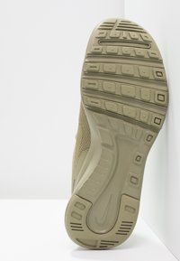 Sole boty Nike v jemné olivové zelené barvě, se texturovanou gumou, obdélníkovými vzory na podrážce, drážkami a brandingem na patě.