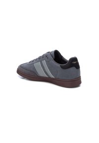 Zapatillas de ante gris con una suela de goma oscura, que presentan dos rayas gris claro y un contrafuerte negro. Cuentan con cordones y acolchado para mayor comodidad.