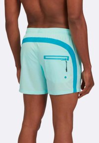 Gli swim shorts azzurri chiari presentano una striscia laterale turchese a contrasto, una tasca posteriore con zip e una vita elastica.