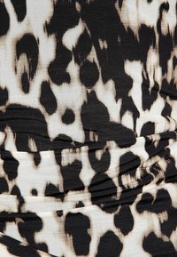 Tissu noir et crème à motif avec un design de léopard ; présente une texture froncée et une surface lisse et douce.