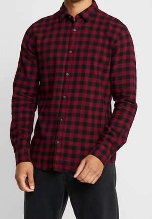 Long-sleeve plaid shirt in red and black with button closure, collar, and fitted design. Fabric appears soft with a medium weight.