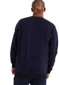 Sudadera azul marino hecha de una tela suave, con cuello redondo, mangas largas y puños y dobladillo acanalados. Textura suave sin patrones visibles.